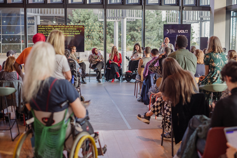 Image of the audience watch an all female panel in a large, light, airy events space.. Cover Image