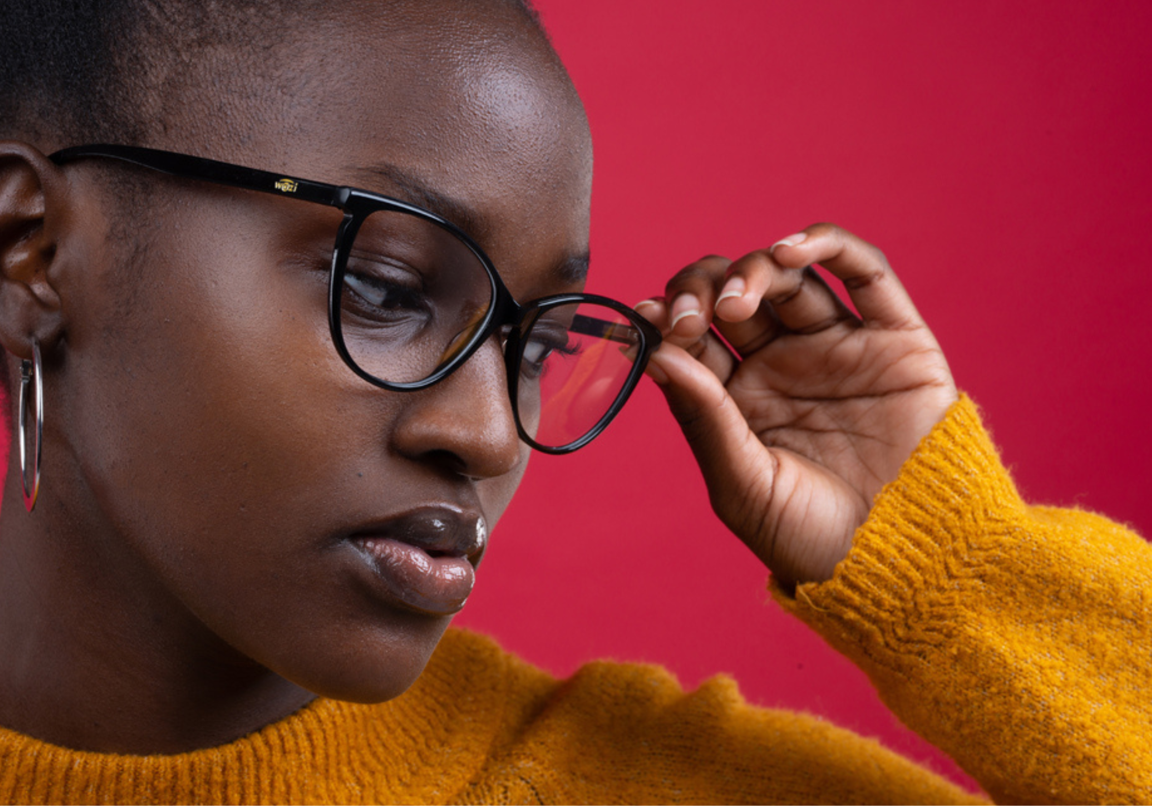 Professional photograph of a woman posing with stylish glasses. The female in the photo is black and is wearing a bright yellow jumper against a red background Cover Image