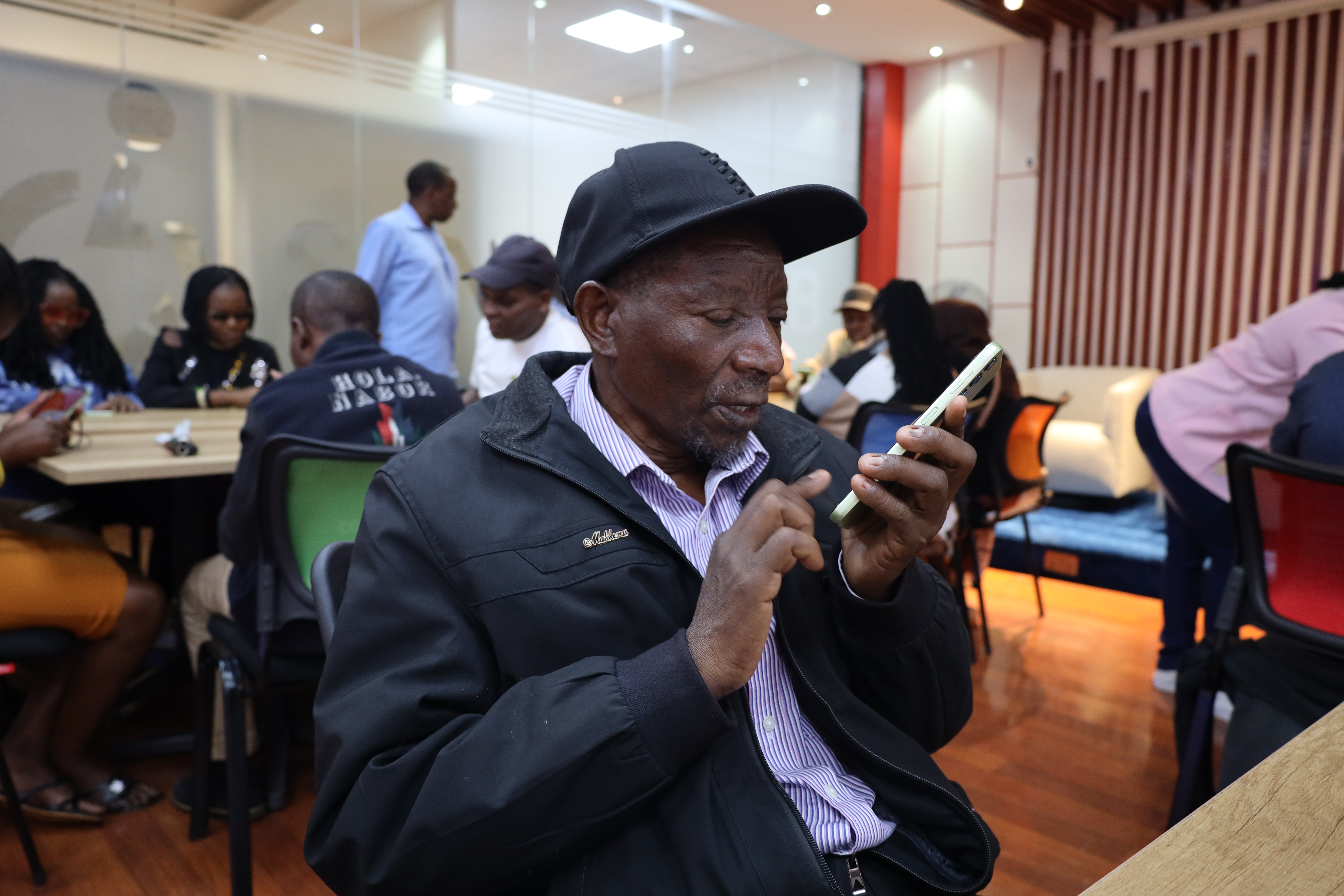 Image of a skills workshop in Kenya with a disabled man testing smart phone features. Cover Image