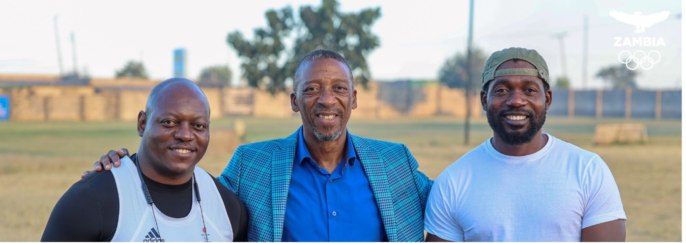 the image shows Richard Lubanza, NOC/CGA Zambia Secretary-General Boniface Kambikambi, and Coach Amon Moyo. (Photo courtesy of Zambia Olympic Committee) Cover Image
