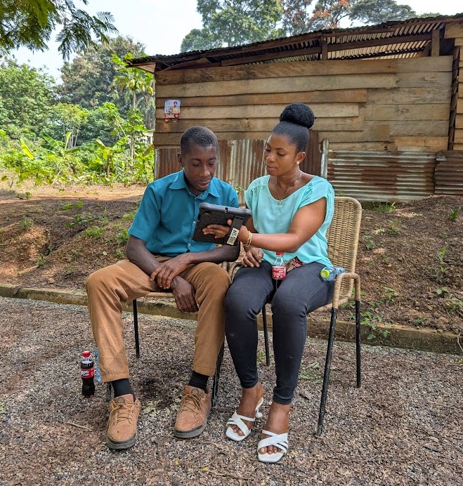 Two people sitting outside and looking at a tablet together - engaged in a training session