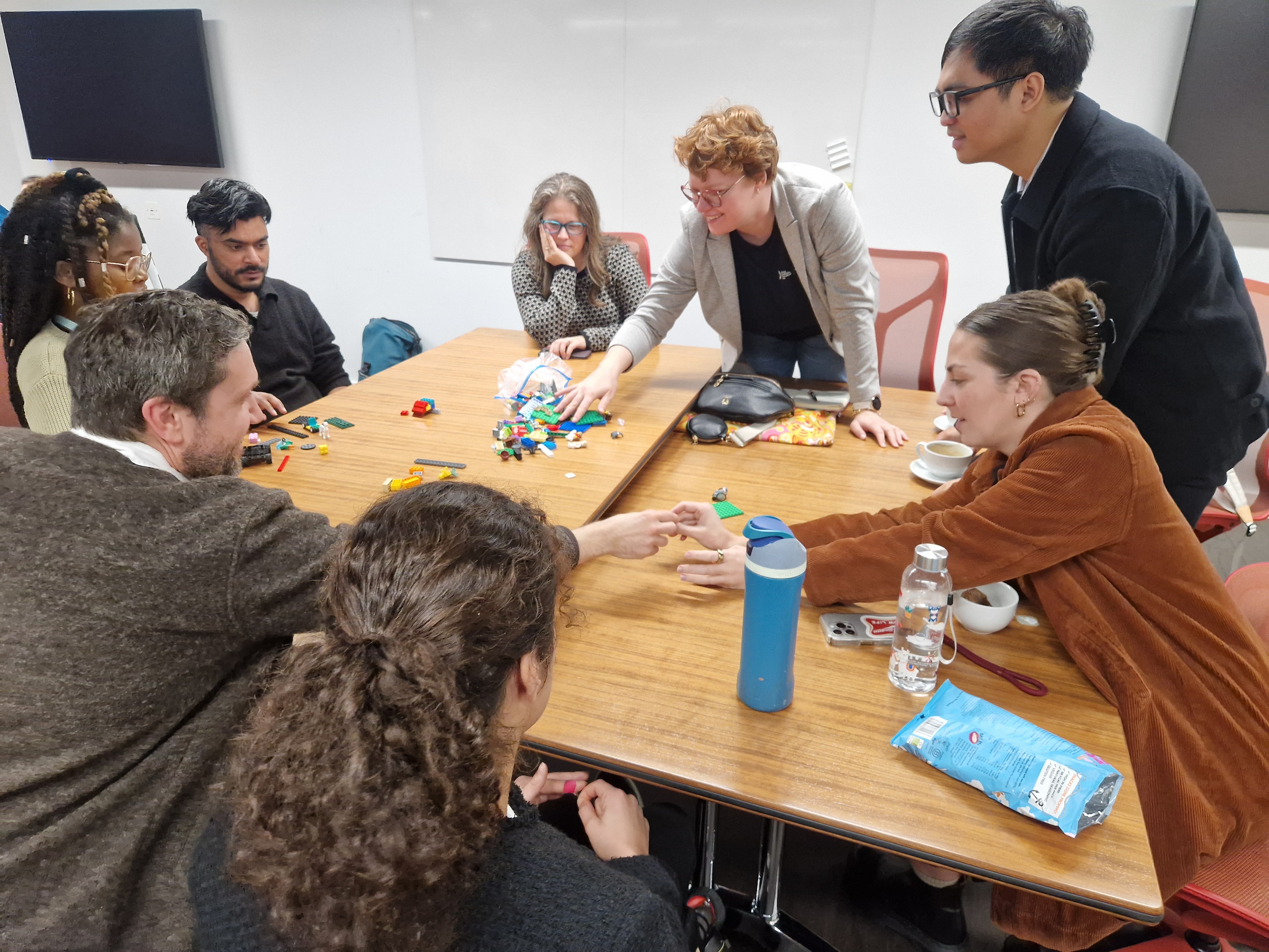 Workshop taking place looking at inclusion - with lots people gathered around a large table using lego to demonstrate