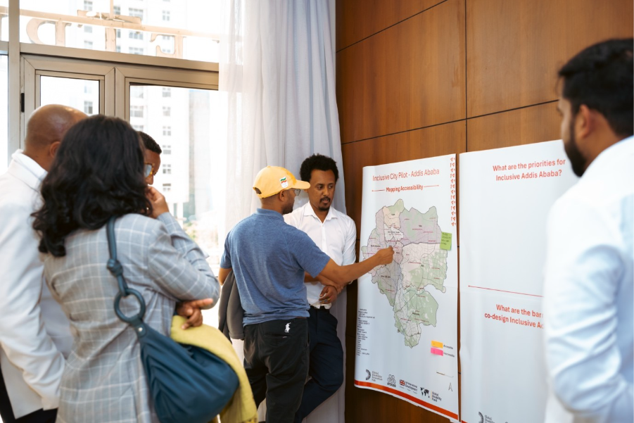 A group of people looking at a map of Addis Ababa diving into its sub-cities, one person is pointing to a section of the map.