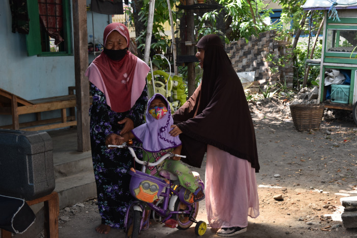 Two women supporting someone on a bike