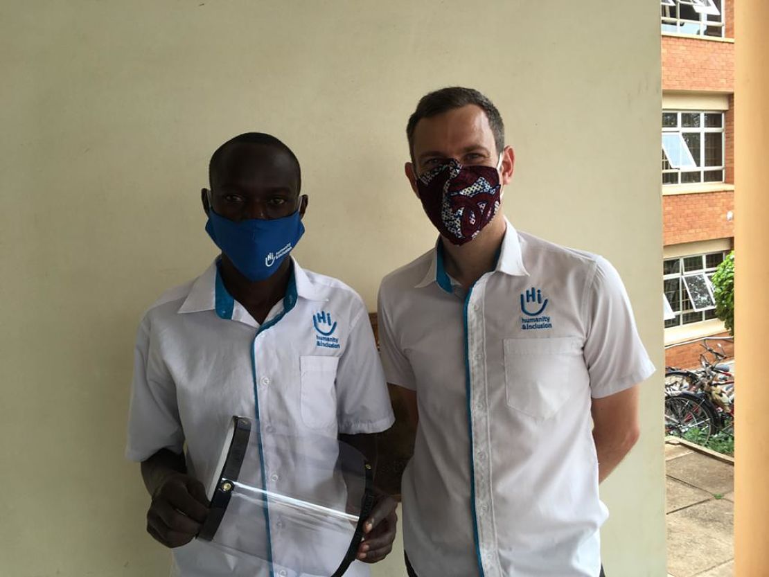 two people stand side by side wearing facemasks