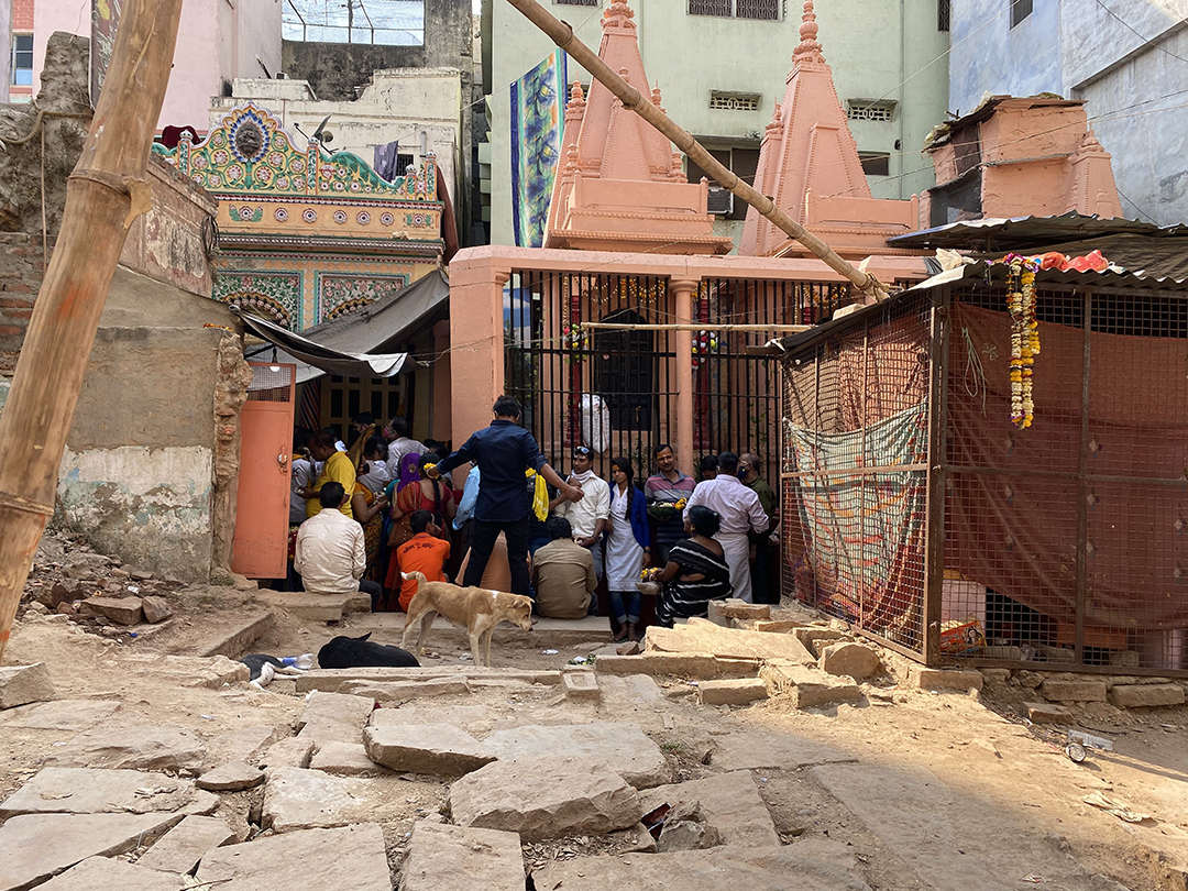 group of people sitting outside a chapel with broken pave stones in the foreground