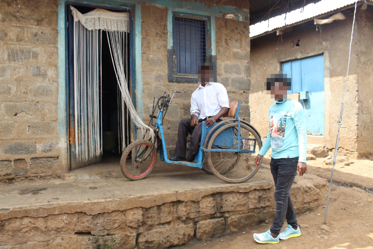 Image of wheelchair on raised area outside of a home - unable to move beween street level and the house