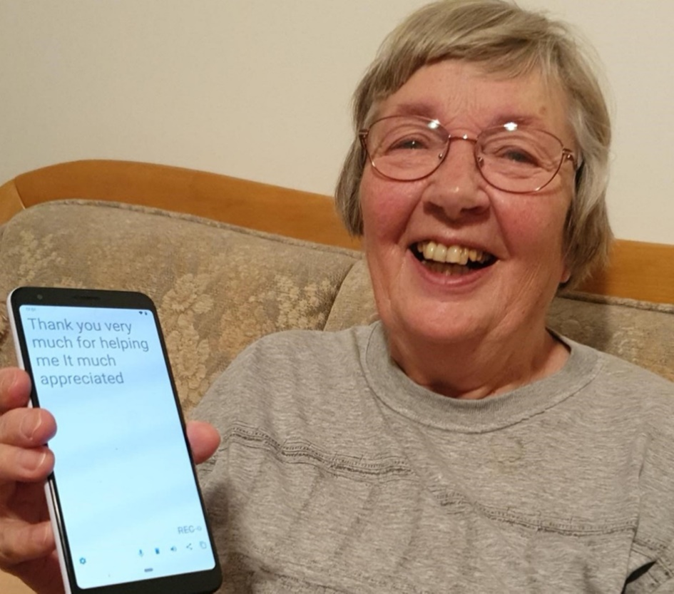 Photograph of a woman holding a phone and smiling. On the phone screen it reads Thank you very much for helping me it much appreciated