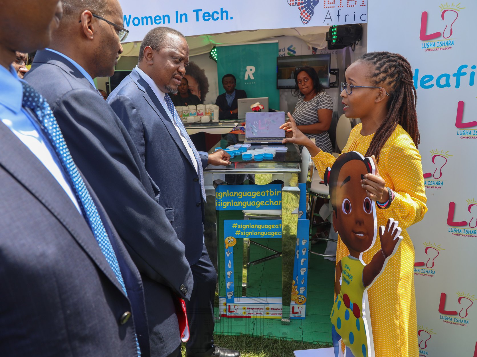 A photo of Nancy on the right speaking to the former president of Kenya (Uhuru Kenyatta) during an exhibition. 