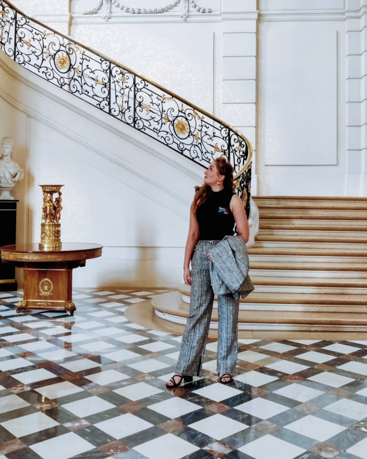 Annamae Muldowney standing in the stairwell of the British Embassy in Paris. She is looking up to the ceiling Cover Image